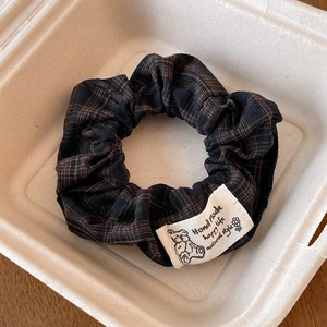 Close-up of a plaid scrunchie with lace edge and cute bear tag in a paper box