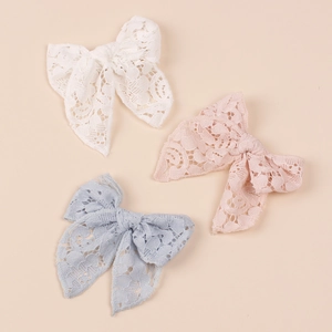 Close-up of lace bow hair clips in white, pink, and light blue for children