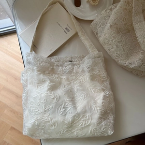 Detailed close-up of floral lace embroidery and fabric texture on a beige tote bag