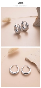 Detailed view of silver titanium steel earrings with ribbed and smooth teardrop textures
