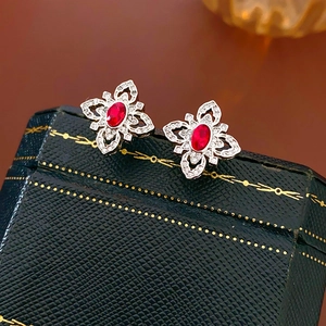 Macro shot of vintage silver earrings featuring a red oval gem and pavé cubic zirconia