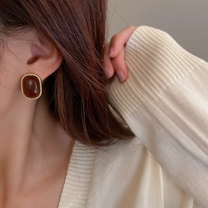 Close-up of vintage square stud earring with amber resin center and gold braided frame