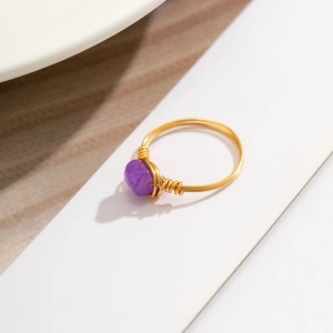Detailed macro view of handmade wire-wrapped gold ring with natural purple amethyst stone