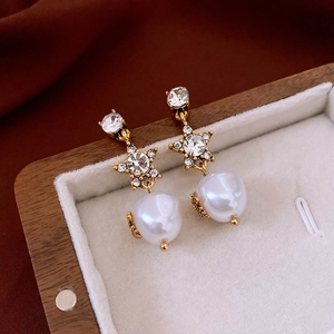 Macro shot of French luxury style pearl earrings with zircon stars in a jewelry box