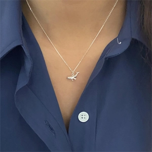 Close-up of a 925 sterling silver whale pendant necklace worn on a blue collared shirt