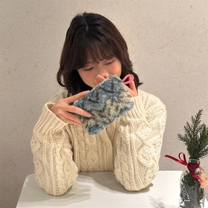 Detail of plush faux fur storage bag with blue-grey marble texture and pink zipper ring