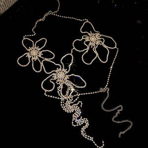 Close-up of sparkling rhinestone flower body chain with adjustable links on black background
