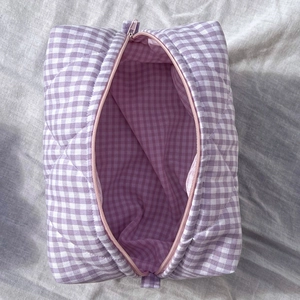 Detail of purple checkered quilted cosmetic bag interior showing spacious lining and texture