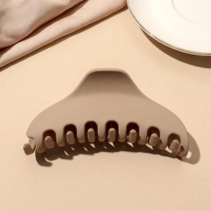 Close-up of matte khaki hair claw clip showing textured finish on aesthetic background