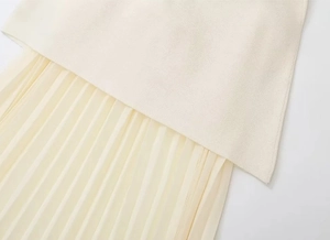 Détail de couture entre le corsage en tricot blanc cassé et la jupe plissée en mousseline