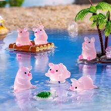 Close-up of translucent pink pig miniatures in a beach-themed micro landscape scene