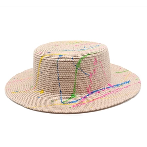 Detailed texture of flat top straw hat featuring colorful artistic paint splash patterns