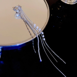 Macro shot of silver tassel earring with sparkling rhinestones and elegant white pearls