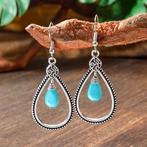 Detail of vintage bohemian teardrop earrings with turquoise stones on a branch