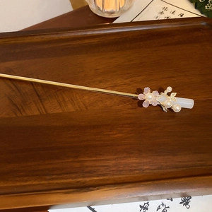 Detailed close-up of a golden metal hair pin with pink resin flowers and white pearls