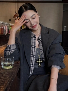 Close-up of a vintage black and gold cross necklace pendant on a male model in a cafe