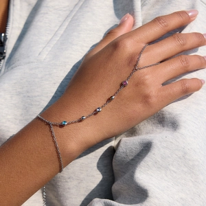 Silver-toned hand chain with colorful circular gemstones on 18K stainless steel bracelet