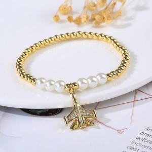 Close-up of pearl stretch bracelet featuring a micro-paved fighter jet airplane pendant