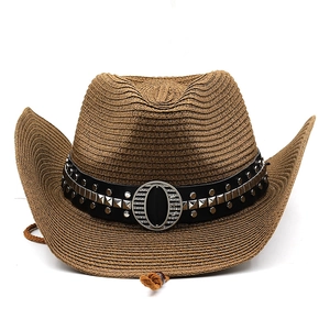 Detail of woven straw cowboy hat featuring metal studs and a brown chin strap