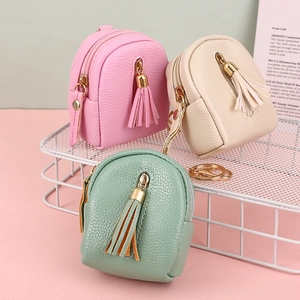 Close-up of three mini backpack coin purses with litchi texture and leather tassels