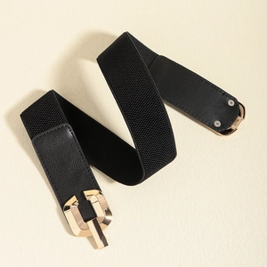 Detailed close-up of golden geometric metal buckle on black elastic waist belt