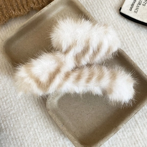 Gros plan détaillé de pinces à cheveux en peluche rayée tons marron chaud et blanc