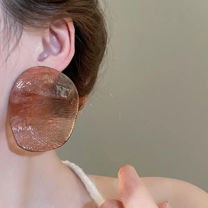 Close-up of model wearing irregular amber resin hoop earrings with textured finish