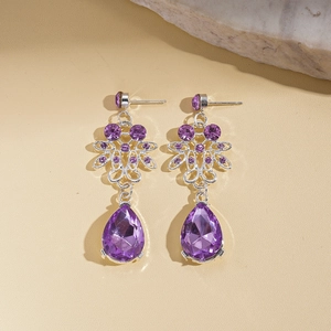 Detail of luxury teardrop earrings with purple crystals and floral silver plating
