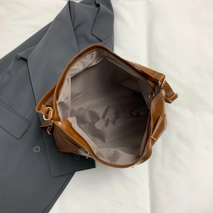 Brown leather tote bag interior with zipper closure on dark grey blazer background