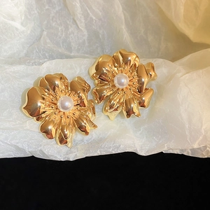 Detail of vintage gold flower earrings featuring a textured metal finish and center pearl