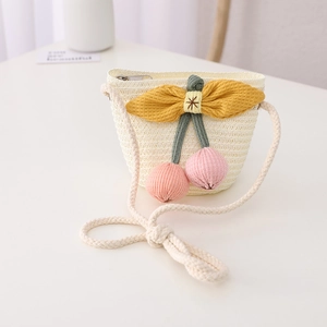 Close-up of kids straw crossbody bag with yellow bow and pink cherry charms