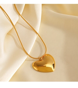 Close-up of golden heart pendant on a snake chain over soft beige silk fabric