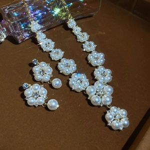 Close-up of elegant flower pearl necklace and earrings set with sparkling rhinestones