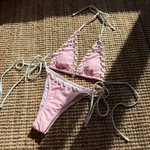 Close-up of pink bikini set featuring white lace-up straps and metal eyelet details