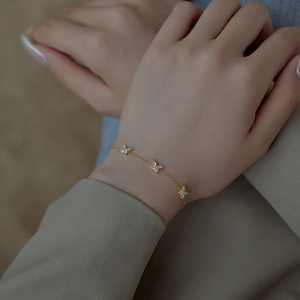Detail of gold clover bracelet with sparkling zircon stones on model's wrist