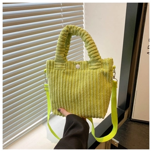 Detailed view of light green corduroy bucket bag featuring vertical texture and white snap button