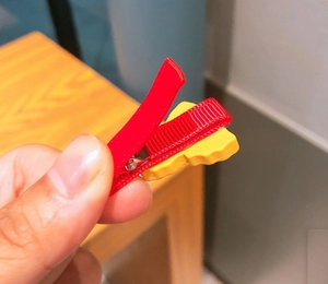 Close-up of a festive red ribbon hair clip with a yellow resin potato chip ornament
