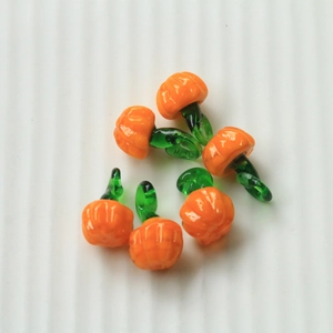 Detailed view of orange glass pumpkin charms with green loops for jewelry making