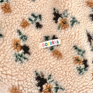 Macro view of plush sherpa fleece fabric with floral patterns and woven brand label