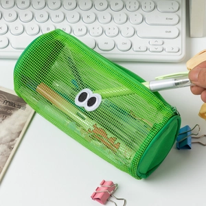 Detail of green mesh pencil case with cartoon eyes on a desk with keyboard