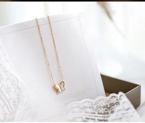 Close-up of golden butterfly necklace with white mother-of-pearl inlay on elegant lace