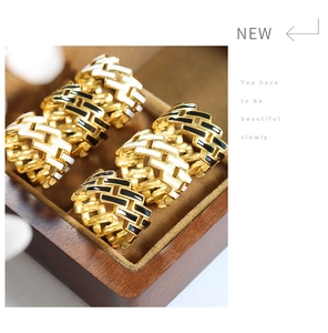 Close-up of gold-plated woven rings with black and white enamel in a luxury wooden box
