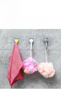 Three multi-color adhesive wall hooks holding towels and bath sponges in a bathroom