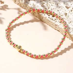 Elegant gold and rose pink beaded stretch bracelet on a minimalist textured stone base