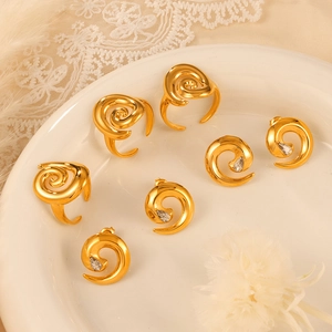 Elegant gold spiral jewelry set with rings and gemstone earrings on white lace background