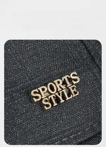 Detail of the SPORTS STYLE metal logo plaque on premium dark grey baseball cap fabric