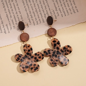 Detailed view of vintage acrylic leopard flower drop earrings on a retro book page