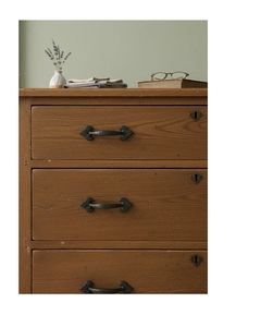Close-up of vintage matte black cast iron drawer handle on a classic wooden cabinet