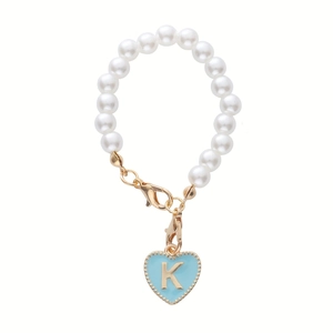Detail of pearl cup accessory featuring a blue heart charm with golden letter K