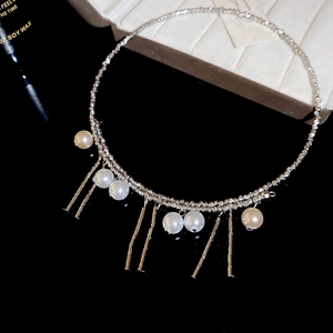 Detailed macro view of silver tassel choker with pearls and metallic fringe on black stand